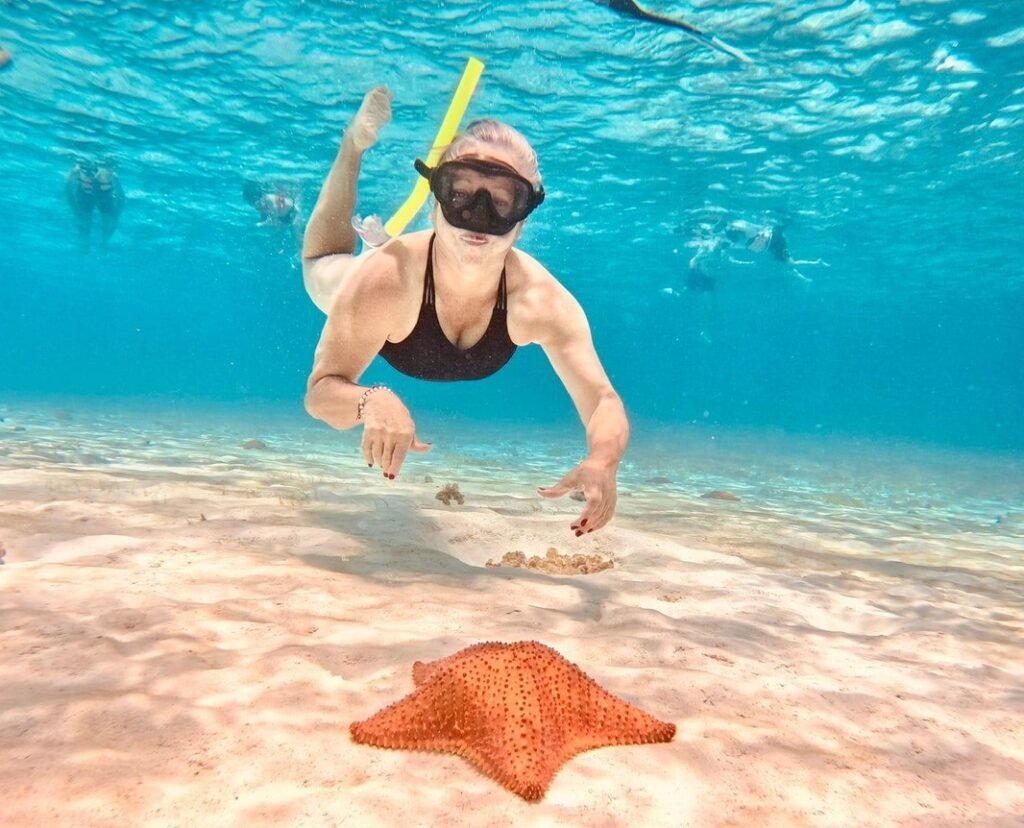 Buceador nadando cerca de estrella de mar.